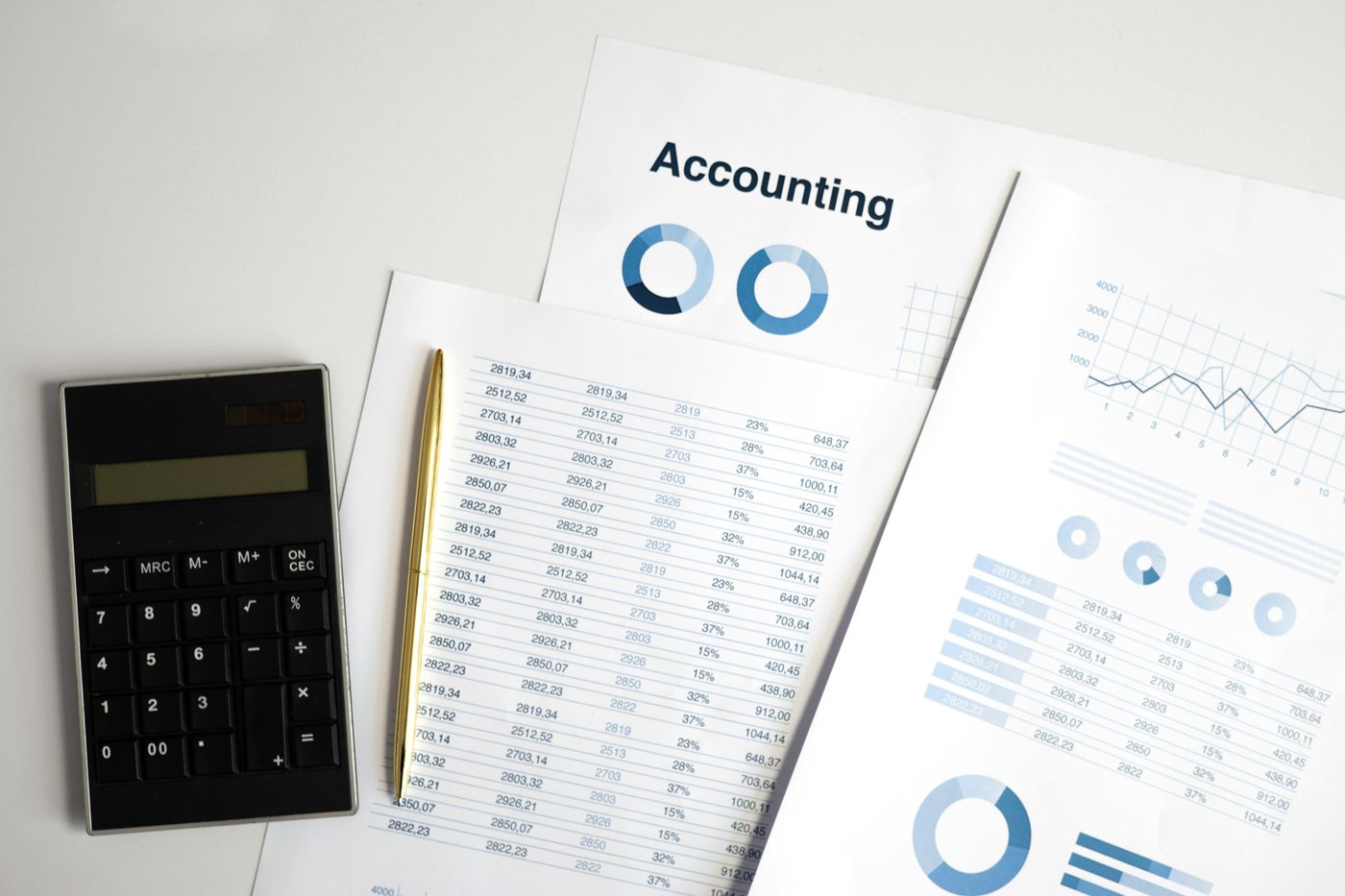 Accounting documents, a calculator and a laptop on a desk