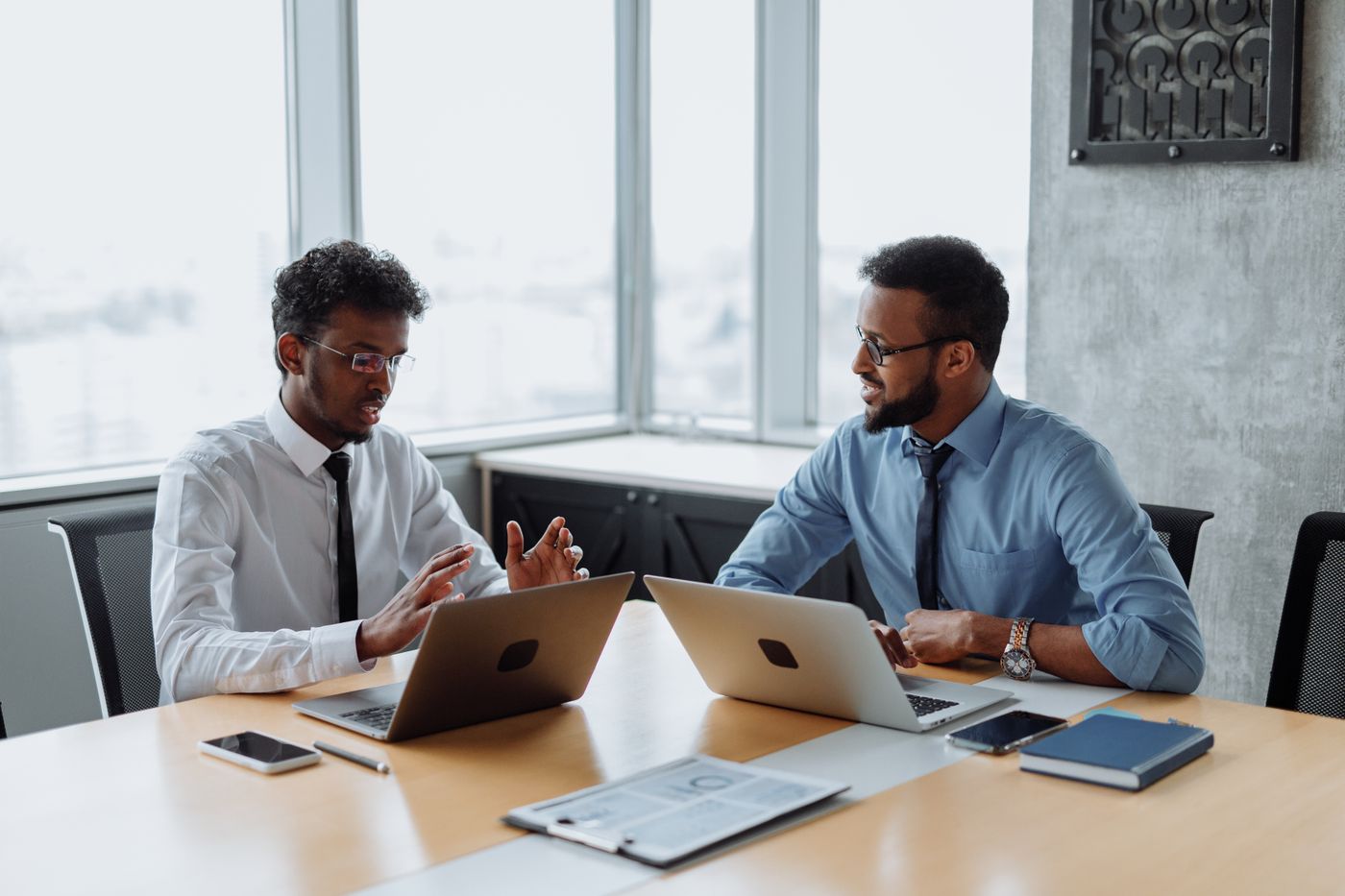 Two African professionals discussing work beside a laptop