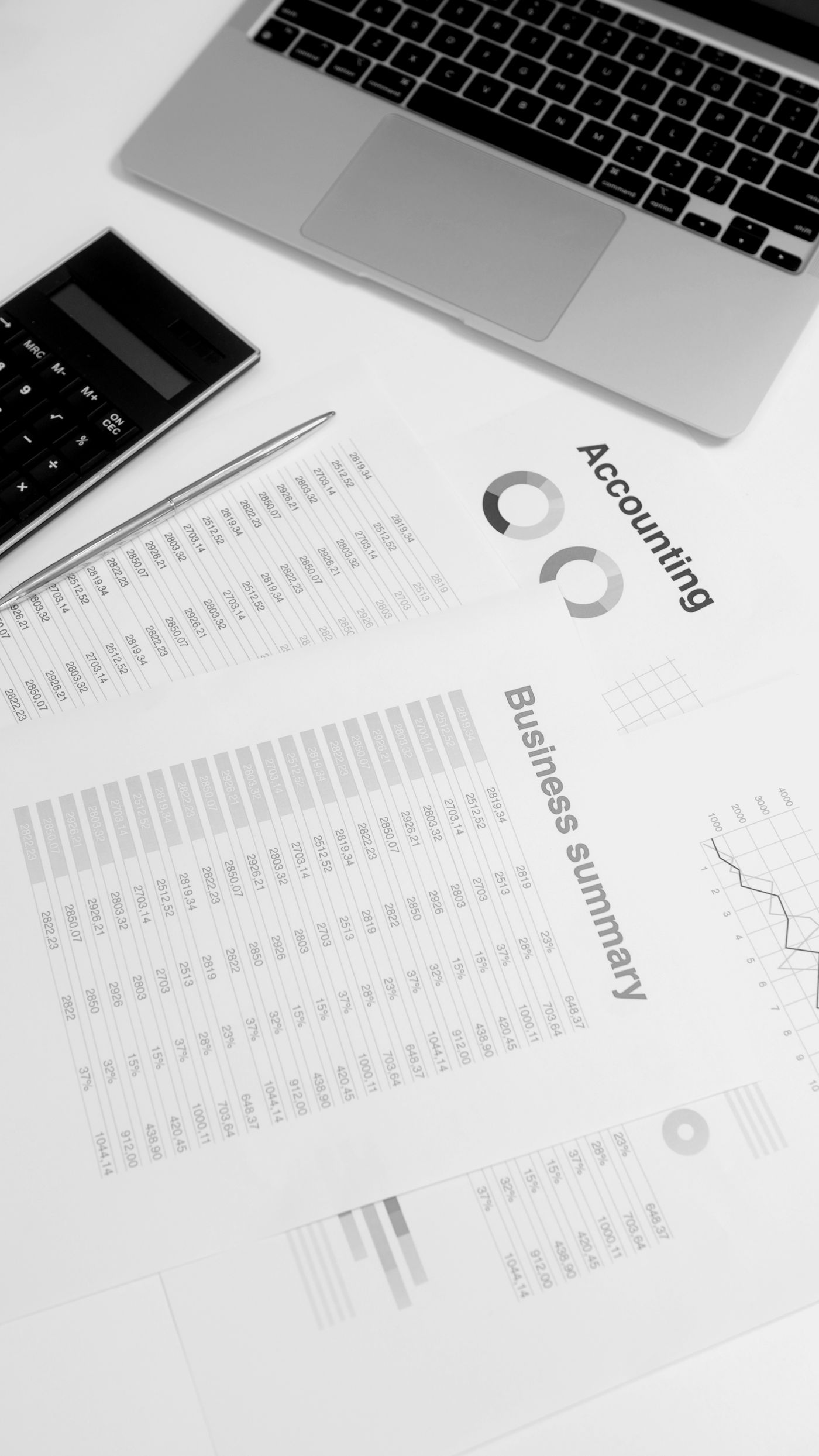Financial reports, a laptop and a calculator arranged on a desk